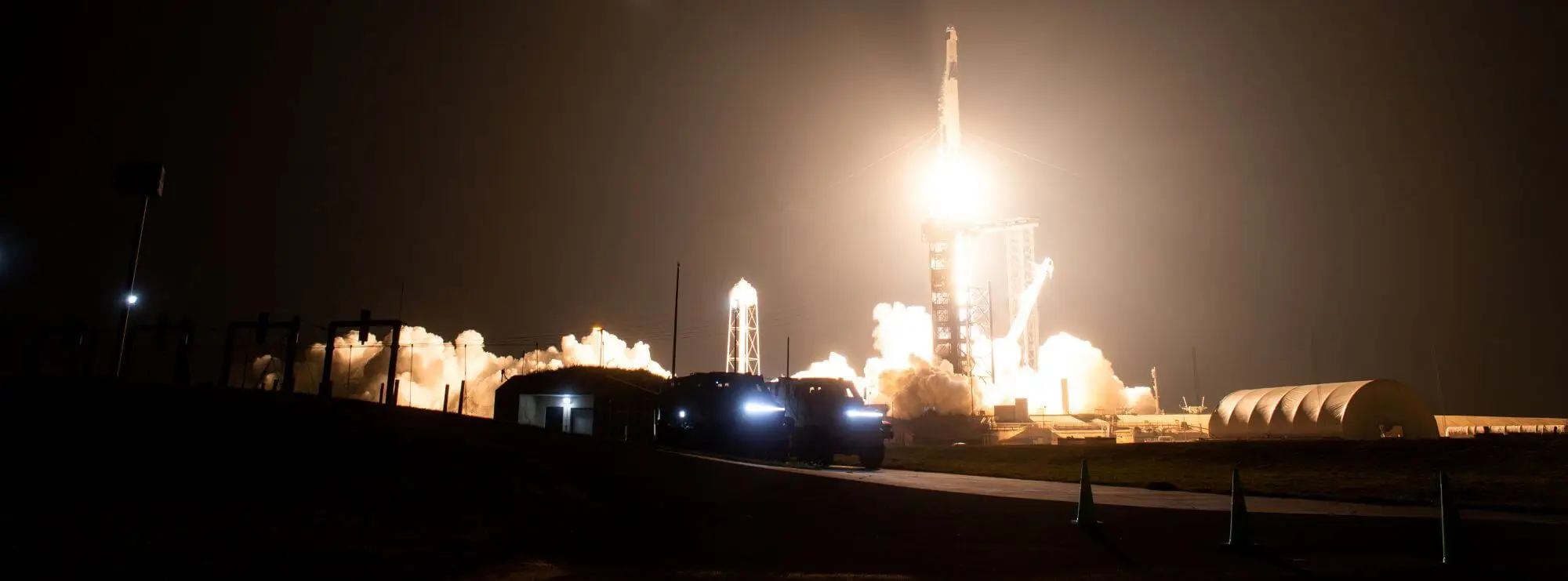 A SpaceX rocket lifts off at night, its engines lighting up the launch pad against a dark sky