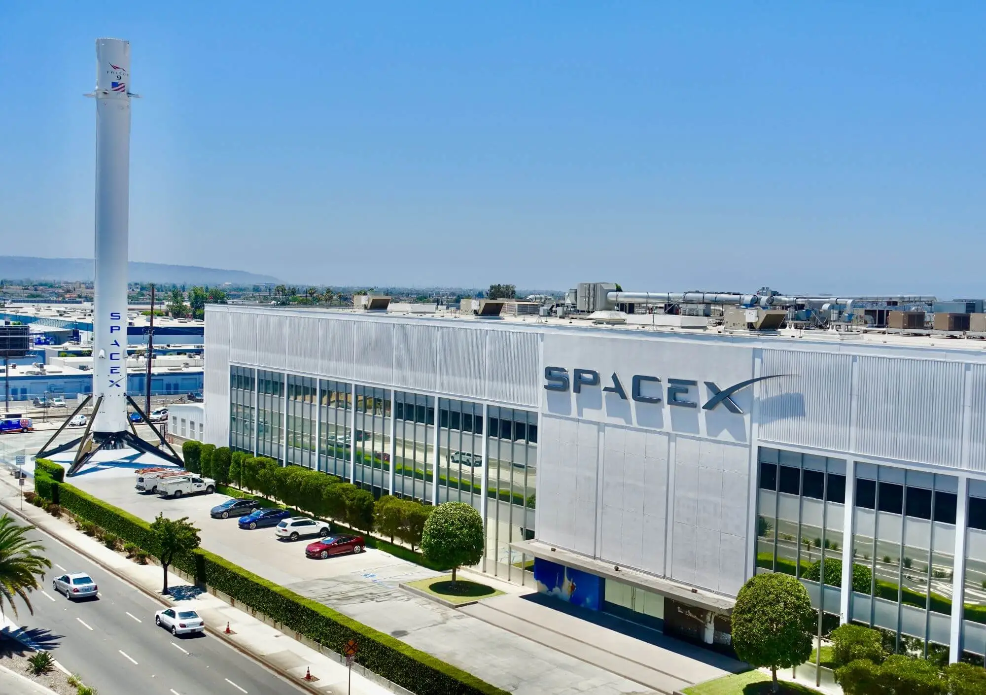 SpaceX headquarters in Hawthorne, California, with a recovered Falcon 9 booster standing outside the building